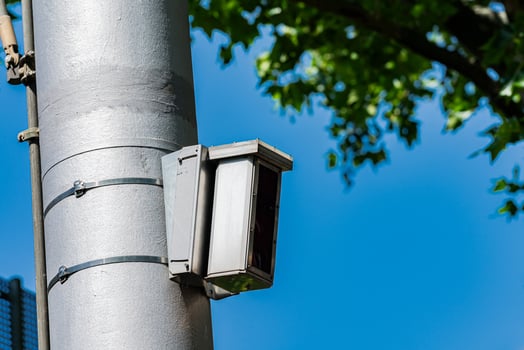 A surveillance camera attached to a tall pole monitors the street photo