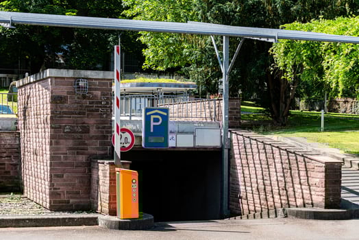 A well-maintained parking garage entrance is shown, framed by lush photo