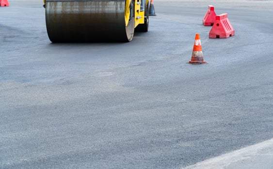 Vibratory road roller.Plastic road fencing on the road. Road construction photo
