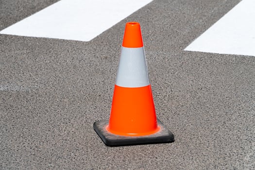 Bright orange traffic cone standing on asphalt photo