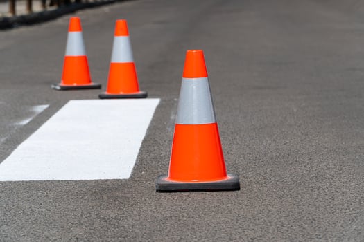 Orange construction cones on an asphalt road. Newly painted striped road markings of a pedestrian crossing photo
