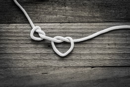 Two knot on rope a heart on vintage wooden background photo