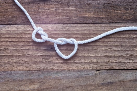 Two knot on rope a heart on vintage wooden background. photo