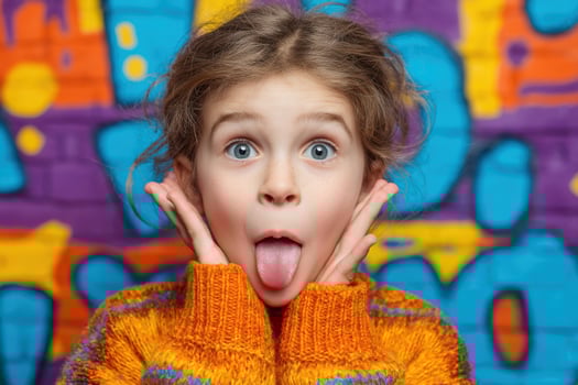 A young girl sticking out her tongue in front of a graffiti wall photo