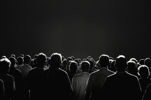 Large group of people standing together in silhouette, focused on an unseen performance as they share a collective moment of excitement photo