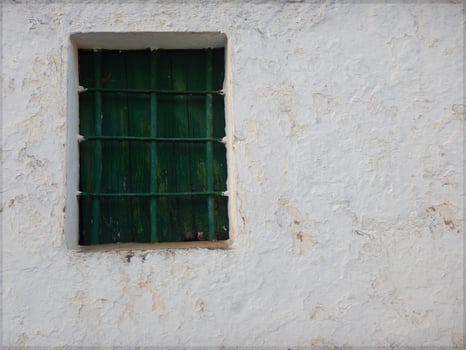 Old green wooden window in an old white facade photo