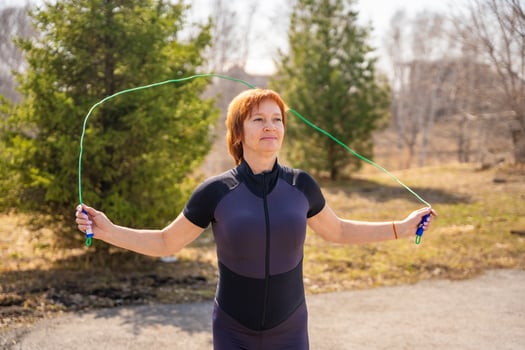 Woman jumping rope during morning workout in a green park. Cardio training, coordination, and energetic outdoor lifestyle. High quality photo
