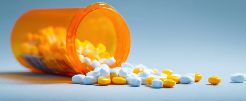 The spilled pills from an orange prescription bottle on a blue surface. photo