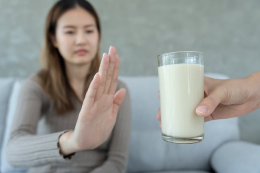 Milk allergen, woman confused milk, runny stuffy sore nose suffer from intolerance allergy trigger symptoms. abdominal pain, allergens, nut protein, rash, death, food allergy. photo