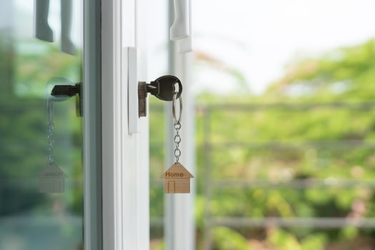 Landlord key for unlocking house is plugged into the door. Second hand house for rent and sale. keychain is blowing in the wind. mortgage for new home, buy, sell, renovate, investment, owner, photo