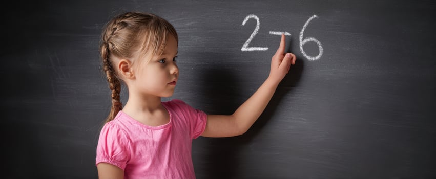 The girl solving a math problem on a chalkboard with concentration. photo