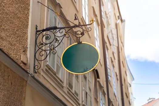 Classic round green signage with gold trim and ornate bracket, perfect for vintage-themed branding, boutique shops or historic district businesses. photo
