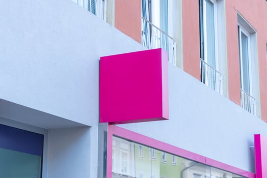 Pink square signage on modern building facade, perfect for fashion, beauty, or retail branding mockups in urban business presentation concepts photo
