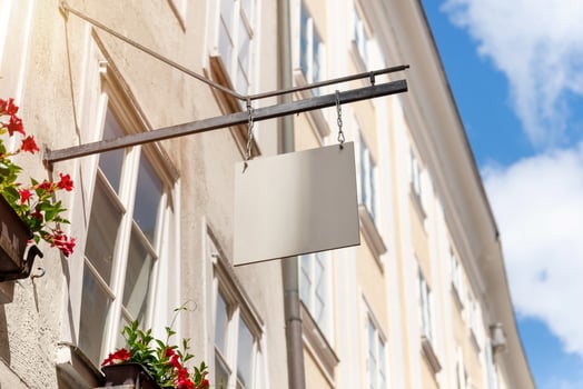 Hanging square shop sign with floral decor and sunny sky, ideal for boutique branding mockups, cafes or local small business advertisements photo