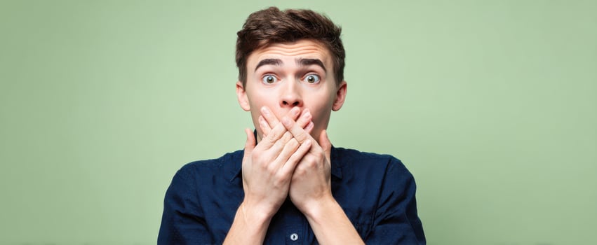 The surprised young man expressing shock with his hands covering his mouth. photo