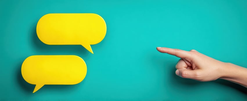 The hand pointing towards vibrant yellow speech bubbles for communication. photo