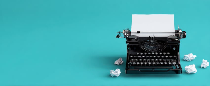 The classic typewriter with blank paper and crumpled drafts on a teal background. photo