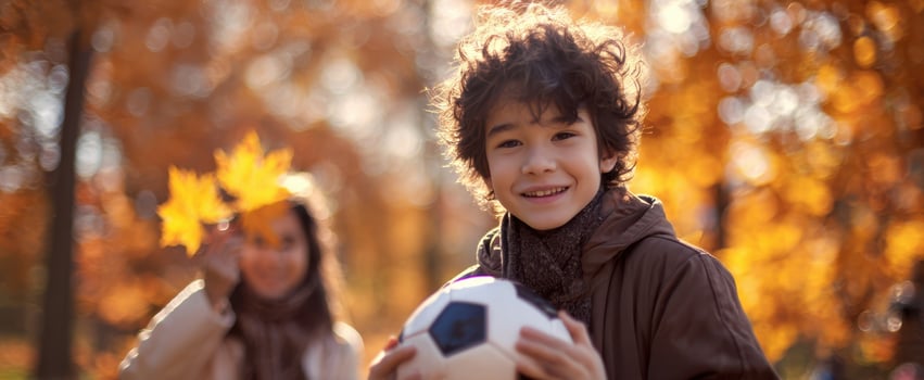 The joyful boy playing soccer with his mother in an autumn park. photo