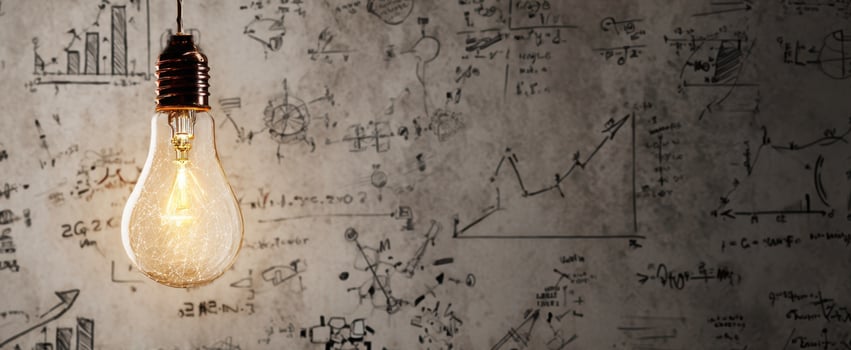 The glowing light bulb against a chalkboard filled with scientific equations and diagrams. photo