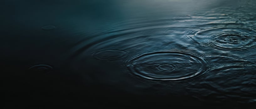 The serene ripples created by droplets on a dark water surface. photo