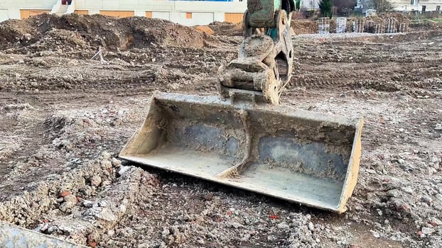 A bulldozers heavy shovel rests on the ground at a busy construction site, ready for excavation work photo