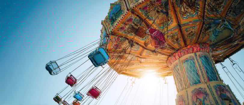 A carnival ride with colorful seats and a bright sun photo