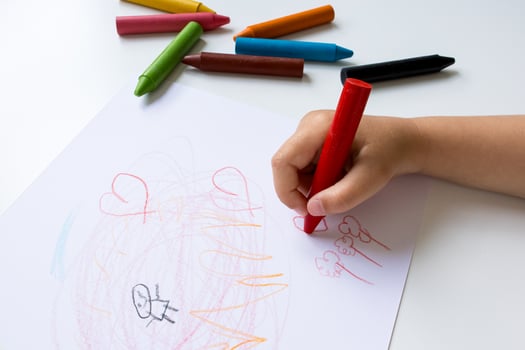 Child hand drawing with crayons on white paper. Creative art activity photo