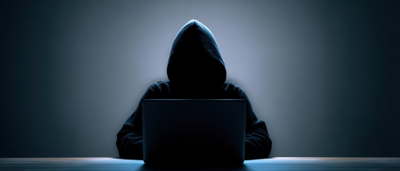 The mysterious hacker intently working on a laptop in a dark setting. photo