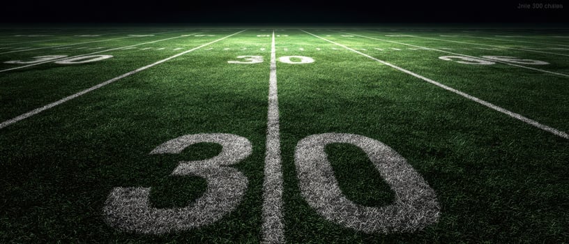 The illuminated football field showcasing the 30-yard line at night. photo