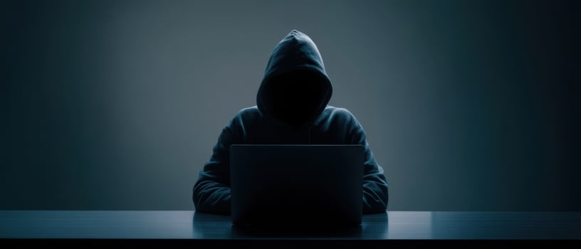 The mysterious hacker working on a laptop in a dark environment. photo