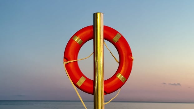 A vibrant and bright red lifebuoy stands prominently against a tranquil and serene seascape during sunset photo