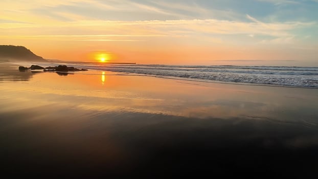 The breathtaking sunset is beautifully reflecting on the calm, tranquil ocean waters accompanied by gentle waves photo