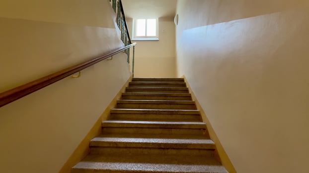 A serene and beautiful view of a welllit, elegant stairway that gracefully leads to a bright window positioned above photo