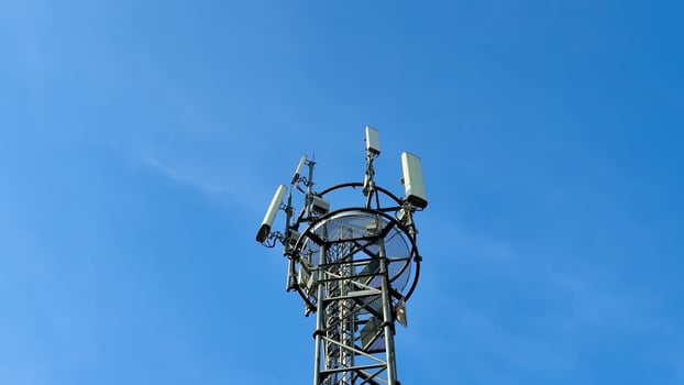 A tall communication tower with antennas looms against a blue sky, symbolizing modern technology and connectivity photo