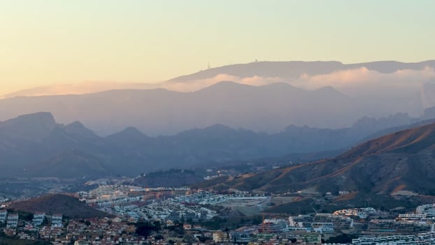 This is a breathtaking view of rolling mountains and fluffy clouds at sunset, showcasing the beauty of nature photo