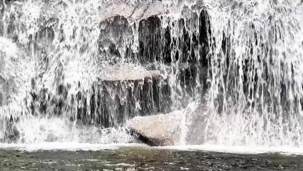 A serene and tranquil view of cascading water flowing gracefully over rocks, capturing the pure beauty of natures flow photo