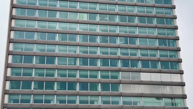 This contemporary office building features a striking, sleek glass exterior with multiple designed floors that impress photo