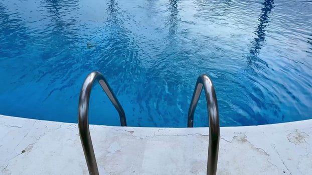 Experience a serene pool view that features elegant palm trees, an urban backdrop, and calm, inviting blue waters photo