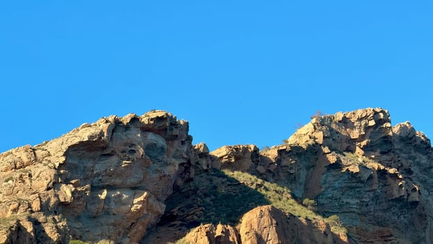 Majestic mountain cliffs that beautifully showcase complex textured rock formations against a bright blue sky photo