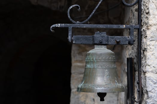 Rustic Bronze Bell Mounted on Weathered Stone Wall in Historical Setting photo