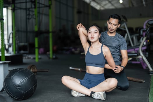 Personal Training and Fitness Coaching. A trainer assisting a woman with stretching exercises in a gym. photo