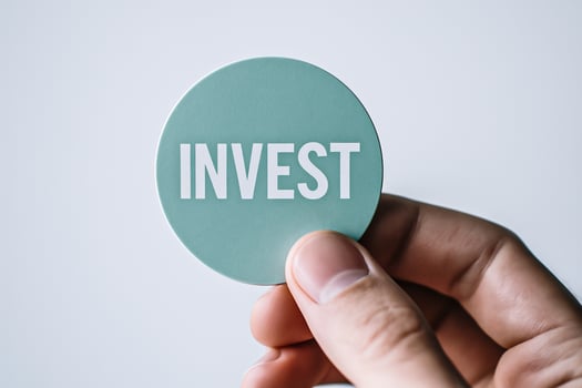 Male hand holding round green sticker with invest text, financial opportunity, economic strategy, capital planning and wealth generation concept photo