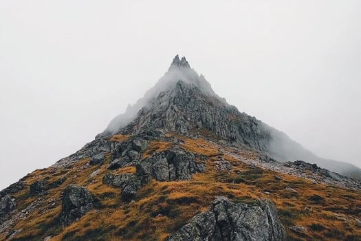 A mountain with a foggy sky and grass photo
