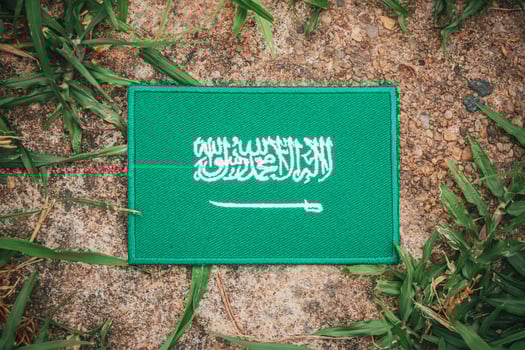 Eco-friendly Saudi flag made from fabric, placed on natural rock with leaves and grass around. Top-view from Middle East theme. Ideal for environmental and Earth Day content. photo