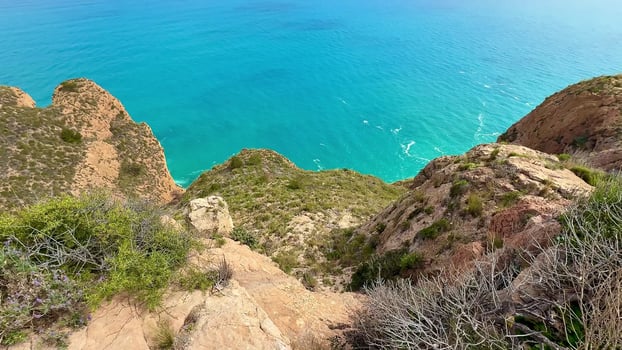 A breathtaking view from the high cliffs featuring lush greenery and the vibrant turquoise sea beneath a clear blue sky photo