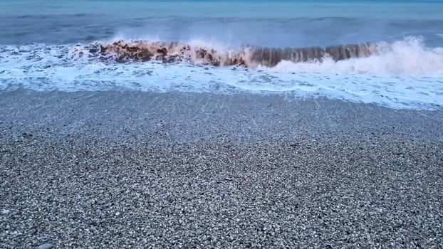 Immerse yourself in the serene and captivating beauty of gentle waves crashing against a pebbled beach during twilight photo