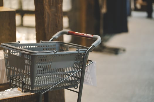 an empty grey plastic shopping basket on a trolley in a modern retail store or supermarket with a blurred background. the retail industry, grocery shopping, daily errands, and commercial advertisement photo
