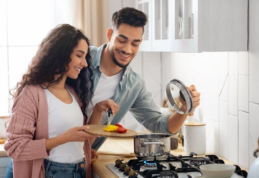Portrait Of Happy Young Arab Couple Cooking Healthy Food In Kitchen Together, Cheerful Middle Eastern Spouses Preparing Tasty Vegetable Lunch At Home, Adding Ingredients To Pan, Closeup Shot photo