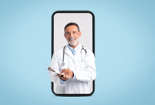 Happy confident european old doctor in white coat with stethoscope makes notes on big phone screen on blue background. App for medical help, diagnostics, exam, ad and offer photo