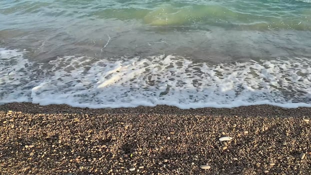 Capture the serene and stunning beauty of ocean waves as they gently wash onto a lovely pebbly shore photo